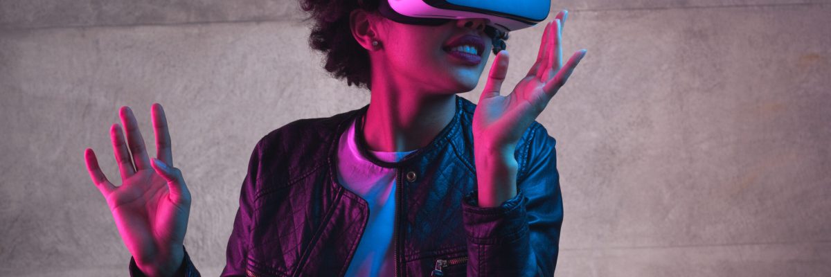 Cheerful girl with hands up wearing the virtual reality goggles.