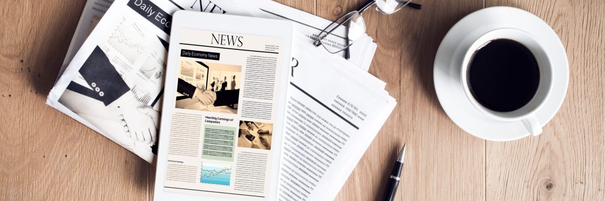 Newspaper with tablet on wooden table