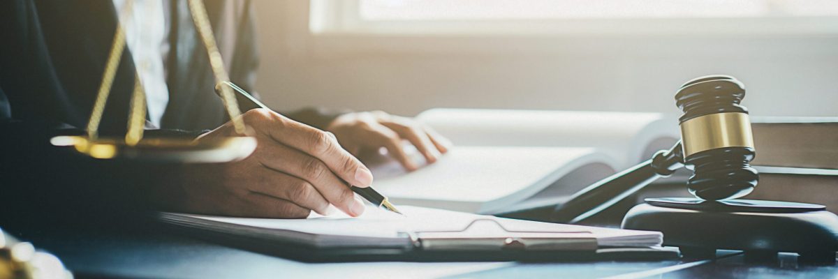 Justice and Law concept. Legal counsel presents to the client a signed contract with gavel and legal law or legal having team meeting at law firm in background