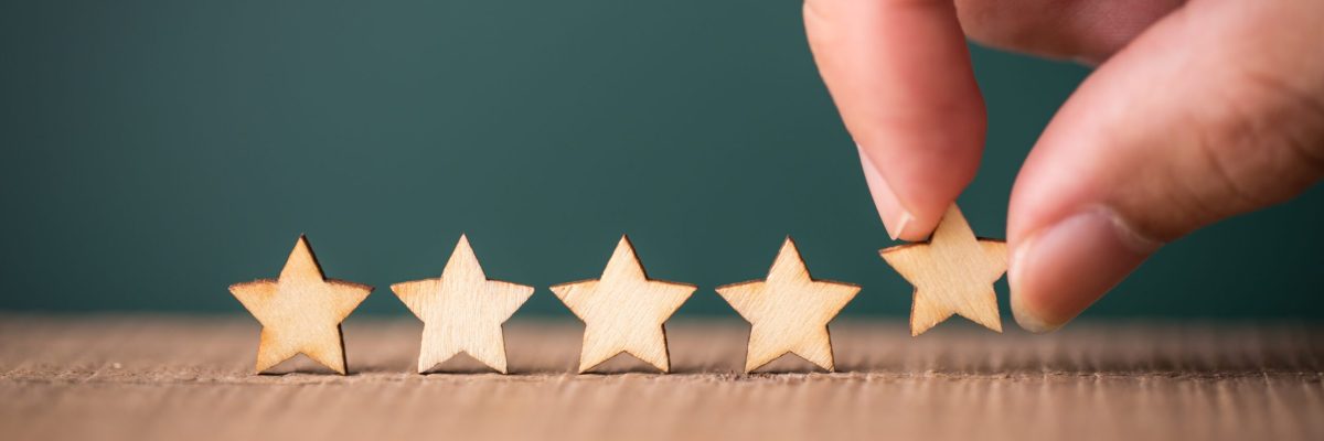 Hand putting wooden five star shape on table. The best excellent business services rating customer experience concept.