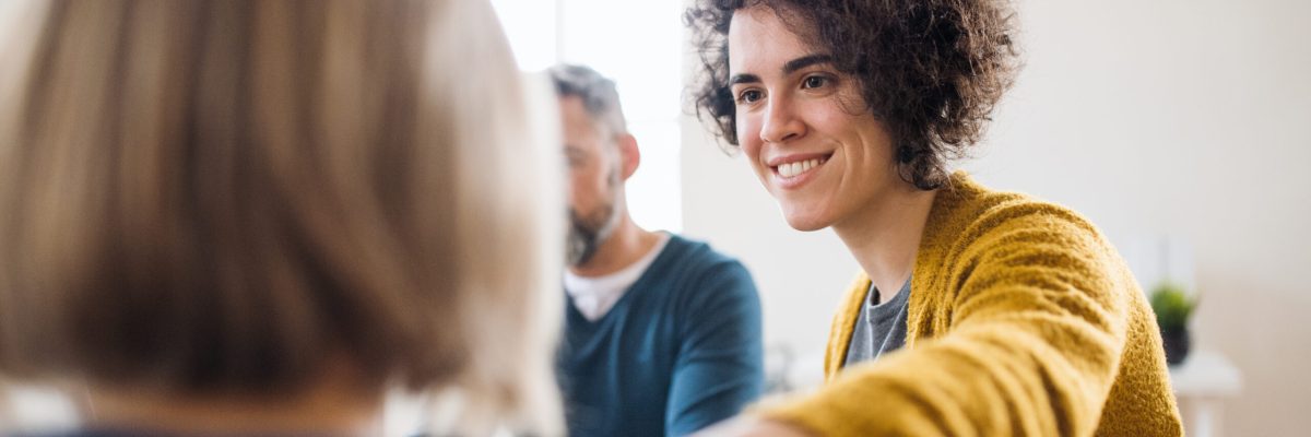 Serious men and women sitting in a circle during group therapy, supporting each other.
