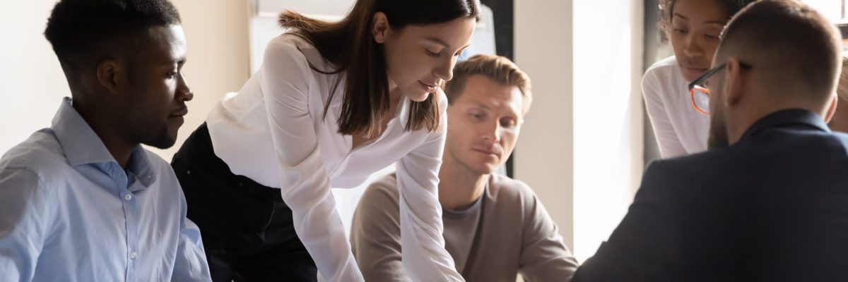 Diverse colleagues working on project together, sitting at table in boardroom, working with legal documents, financial report with statistics, employees engaged in teamwork at corporate meeting