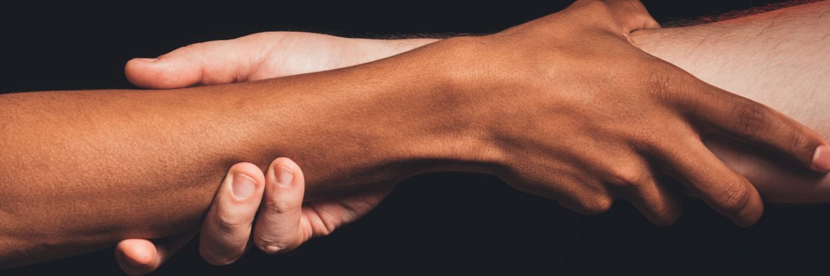 Black lives matter. Peace support. Closeup african caucasian male hands holding together isolated on dark. Racial friendship. Ethnic tolerance. No racism