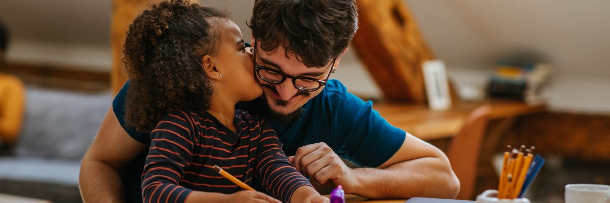 Multiracial father and daughter drawing together at the table at home