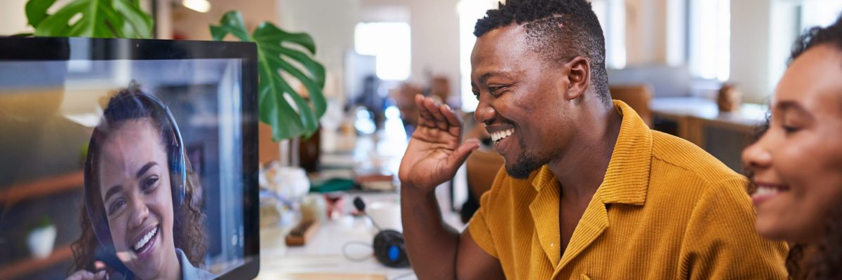 A Black man waves to his colleague on a video call from his office. High quality photo