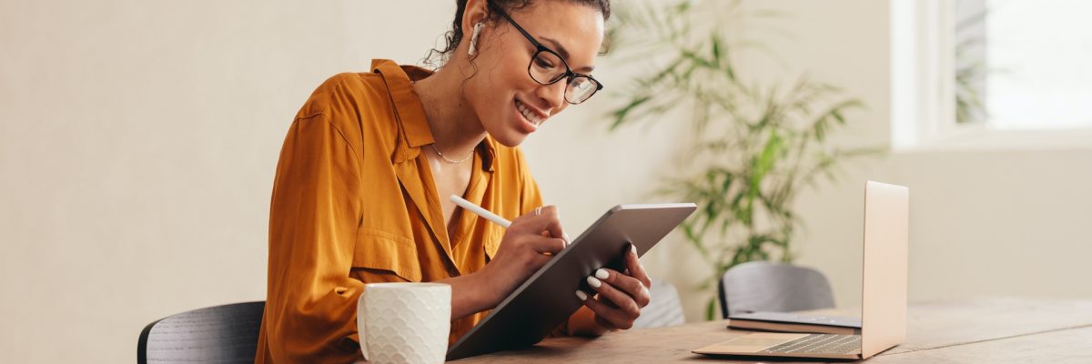 Woman using digital tablet while sitting at home. Female designer sketching on a graphic tablet while working at home.