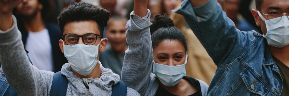 Group of people wearing face mask protesting and giving slogans in a rally. Group of demonstrators protesting in the city.